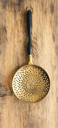 Old used skimmer on a rustic wooden plank, vintage kitchen toolsの写真素材