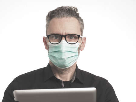 Close up of a businessman with a medical protection mask on a bright backgroundの写真素材