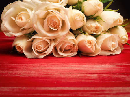 Bouquet of white roses on a red wooden table with space for your textの写真素材