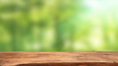 Emtpy wooden table with blurry nature background and flares, space for your text or productの写真素材