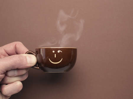 Brown espresso cup with a smiling icon on a brown background, Have a good start to the dayの写真素材