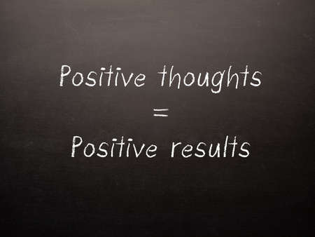 Dark chalkboard with the words positive thoughts give positive results.の写真素材