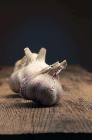 Four bulbs of garlic on a rustic kitchen table, view from above, healthy eating conceptの写真素材