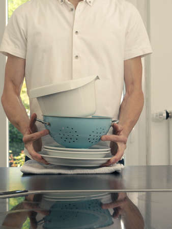 A middle-aged man in a kitchen wish clean dishesの写真素材