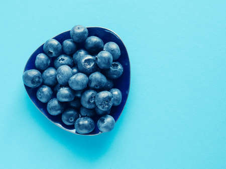 Tasty organic blueberries on a blue paper background with space for textの写真素材