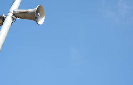 Loudspeakers on a lamppost against a blue summer sky with space for textの写真素材