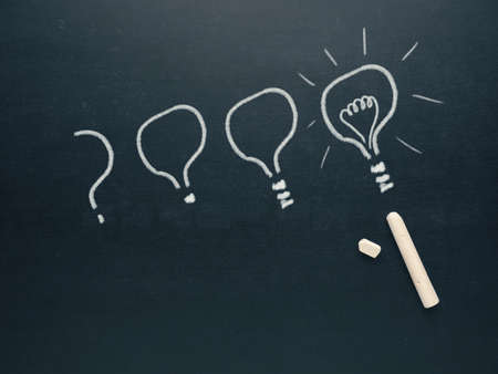 Hand drawn light bulb on a blackboard, a question becomes an idea, creativity conceptの写真素材