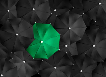 Concept image with lots of black umbrellas and a green umbrella that stands out, be uniqueの写真素材