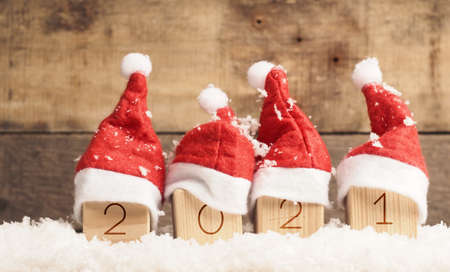 Hat of Santa on a wooden block with the year number 2021, Christmas background, panoramic viewの写真素材