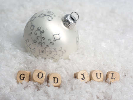 Small wooden blocks with the Scandinavian inscription Merry Christmas in the snow with a Christmas...