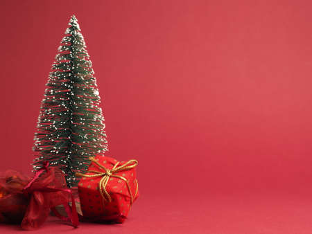 Red Christmas gift box with golden bow and decoration on a red paper background with space for text or imageの写真素材