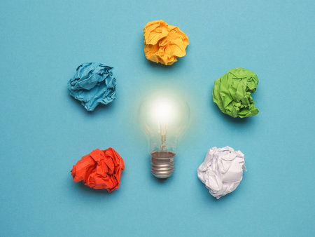 Light bulb with colorful crumpled paper balls on blueの写真素材