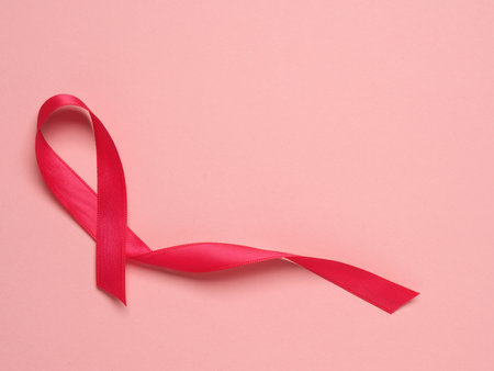 Pink ribbon curl on a pink paper background with copy space, symbol for Liver Cancer awareness, World Cancer Dayの写真素材