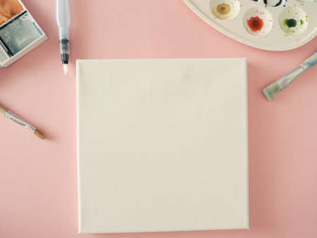 Invitation concept with a blank canvas and watercolors and brushes on a pink background, invitation,...