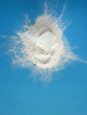 Measuring spoon with protein powder on a blue background, nutritional supplement and healthy diet, vitamin supplementation.の写真素材