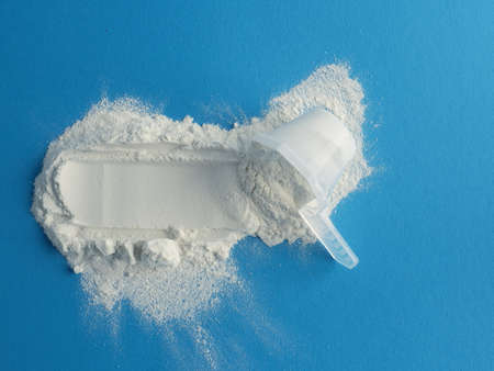 Measuring spoon with protein powder on a blue background, nutritional supplement and healthy diet, vitamin supplementation.の写真素材