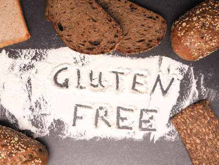 Gluten free written in flour with different types of bread as decoration, healthy food conceptの写真素材