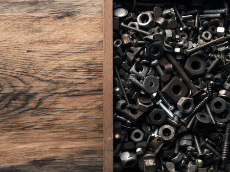 Old rusty bolts and nuts in a wooden box on a workbench
