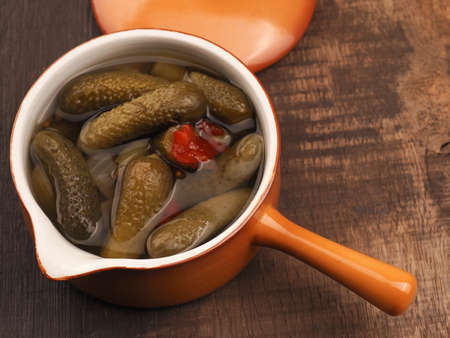 Organic gherkins in a rustic ceramic bowl on a wooden kitchen table, healthy foodの写真素材