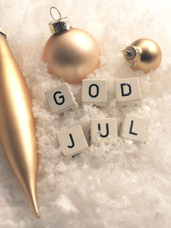 Wooden blocks with God Jul, Scandinavian Merry Christmas in snow with golden Christmas baubles