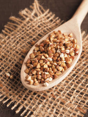 Organic buckwheat on a wooden cooking spoon on a rustic wooden table, close up, healthy food