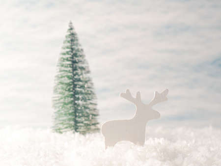 Small reindeer wooden figure in the snow with Christmas tree, space for your text, holiday background or christmas cardの写真素材