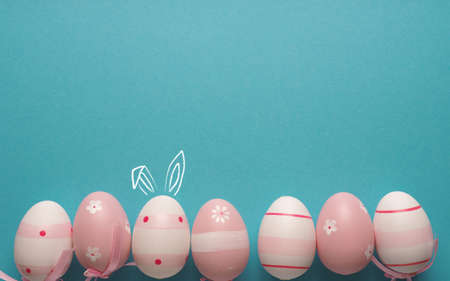 Pink Easter eggs in a row on a blue background with space for text