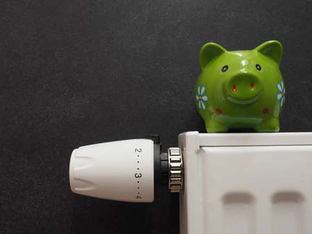 Close up of heating thermostat, saving energy concept with a piggy bank, space for your text, stop...