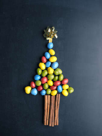 Chocolate peanuts as Christmas tree shape on a blackboard, seasonal food concept