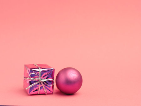 Pink gift box with Christmas bauble on a pink background with space for your text or imageの写真素材