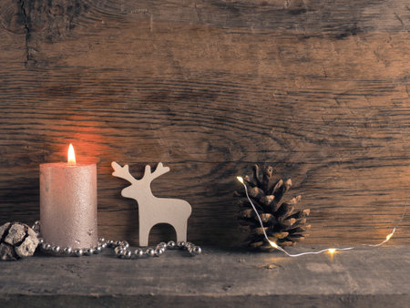 Candle of the first Advent burns, pine cones and Christmas decoration on wood with Christmas lightsの写真素材