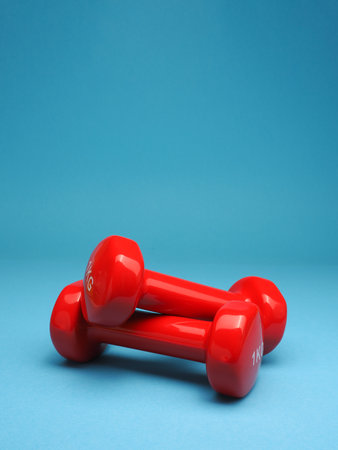 Red dumbbells on a blue background, space for your text, fitness or diet conceptの写真素材