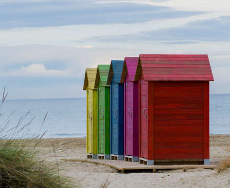 wooden cottages in various colors on the beachの写真素材
