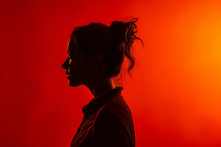 a silhouette of a woman in front of an orange wallの素材