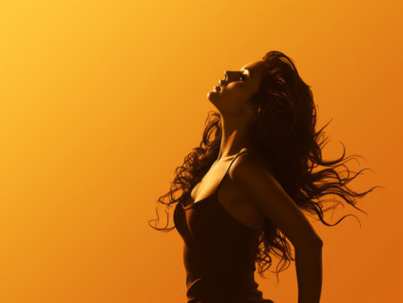 silhouette of a beautiful woman with long hair on an orange backgroundの素材