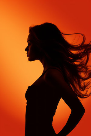 silhouette of a woman with long hair on an orange backgroundの素材