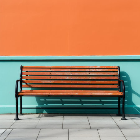 an empty wooden bench against an orange wallの素材