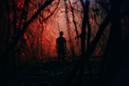 a silhouette of a person standing in a dark forestの素材