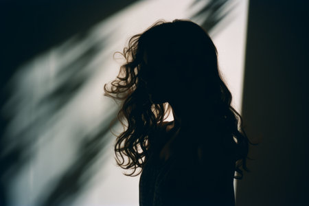 a silhouette of a woman standing in front of a windowの素材