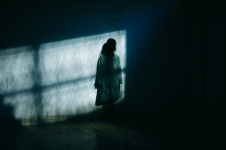 a woman standing in front of a window in a dark roomの素材