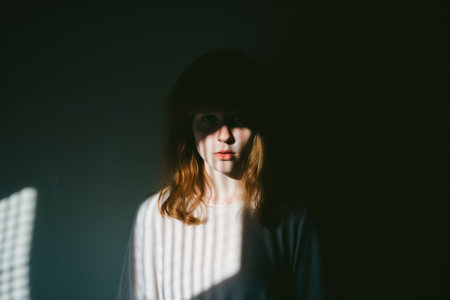 a woman with red hair standing in front of a dark wallの素材