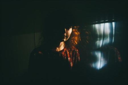 a woman with red hair standing in front of a windowの素材