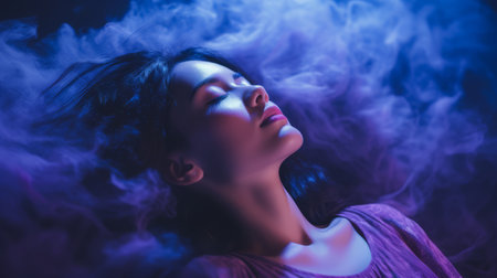 beautiful young woman with purple smoke in her hair lying on a black backgroundの素材
