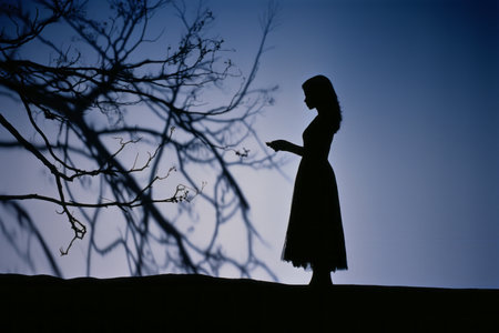 silhouette of a woman standing in front of a treeの素材