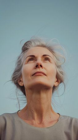 a woman with gray hair looking up at the skyの素材