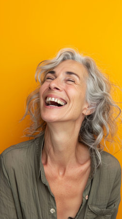 a woman with gray hair laughing and smiling on an orange backgroundの素材