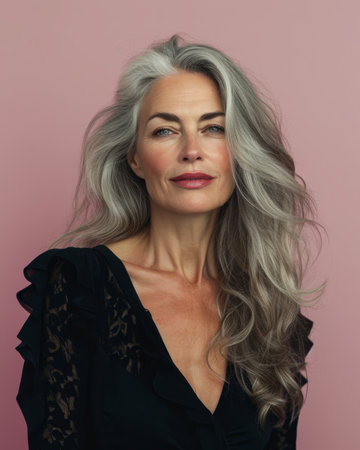 a woman with gray hair posing against a pink backgroundの素材