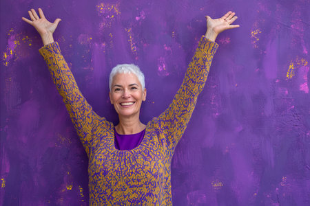 a woman with her arms up in front of a purple wallの素材