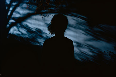 a silhouette of a person standing in front of a treeの素材