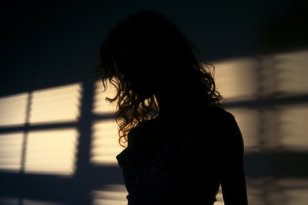 a silhouette of a woman standing in front of a windowの素材